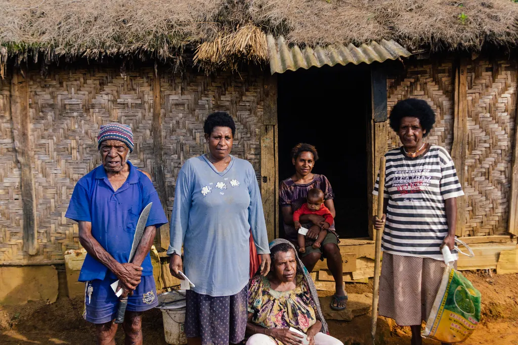 A Papua New Guinea family standing outside their woven bamboo home